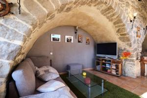 a living room with a couch and a tv in a stone wall at JARDIN STE ANNE in Carcassonne +17 photos