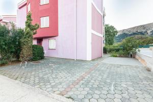 a pink and white building with a stone driveway at Apartments Mimoza in Baška