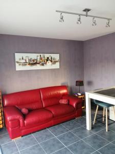 ein rotes Sofa im Wohnzimmer mit einem Tisch in der Unterkunft Appartement 2-3 personnes sur la côte d'Emeraude in Saint-Cast-le-Guildo