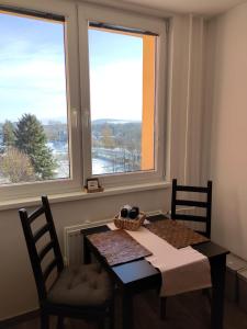 a dining room table with two chairs and two windows at Roses Apartment in Frýdek-Místek