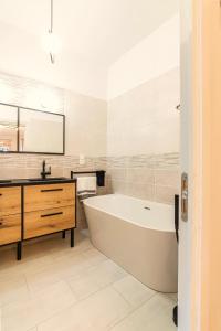 biała łazienka z wanną i umywalką w obiekcie Gîtes dans un mas en pierres au coeur d'un domaine viticole du Pic Saint-Loup w mieście Corconne