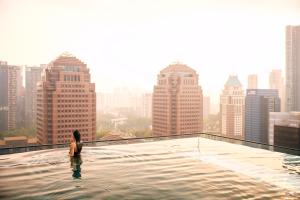 a woman in a infinity pool on the roof of a building at COMO Metropolitan Singapore in Singapore