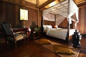 a bedroom with a canopy bed and a chair at Devi Kampot Resort at Phum Kampot in Kampot