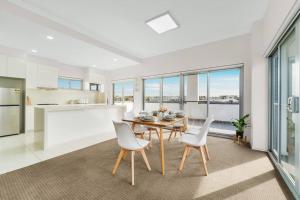 uma cozinha e sala de jantar com mesa e cadeiras em Spacious 3 bed apartment near airport with parking em Sydney