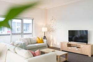 uma sala de estar com um sofá branco e uma televisão em Spacious 3 bed apartment near airport with parking em Sydney