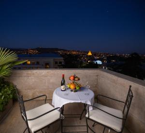 a table with a bottle of wine and fruit on a balcony at Citrus Hotel in Tbilisi City