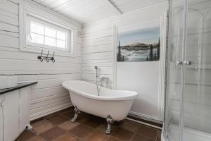 a white bathroom with a tub and a shower at Namsentunet in Grong