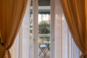 una puerta de cristal abierta con cortinas y una silla al aire libre en Gattamelata Fiera Lodge, en Milán