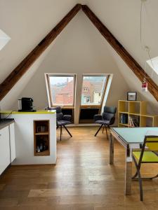 een zolderkamer met 2 ramen en een tafel en stoelen bij Moderne Apartments in attraktivem Altbau in Freiburg im Breisgau