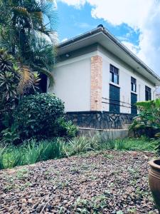 a white house with a palm tree in front of it at Reverie Villa in Mutungo