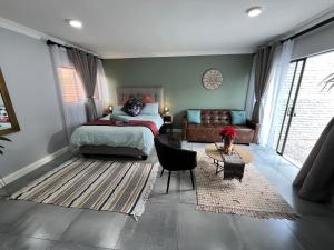 um quarto com uma cama, um sofá e uma mesa em Afrique134 Olive Tree Private Courtyard Suite em Pretoria