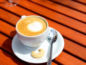 uma chávena de café e uma bolacha num prato em Winzercafe Neipperg Ferienwohnungen em Brackenheim