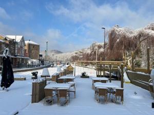 een groep tafels en stoelen bedekt met sneeuw bij Hotel Val De La Cascade in Stavelot