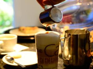 eine Person, die Kaffee in eine Tasse auf einem Tisch gießt in der Unterkunft Winzercafe Neipperg Ferienwohnungen in Brackenheim