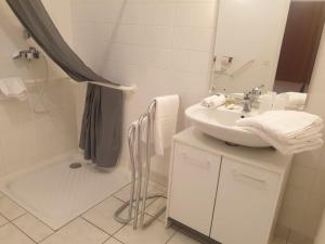 a white bathroom with a sink and a shower at Auberge du Couesnon in Vendel