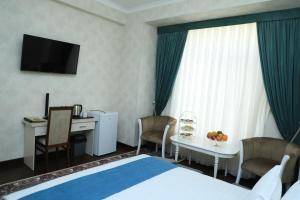 Habitación de hotel con cama, mesa y escritorio. en Poykent Naqshband, en Bukhara