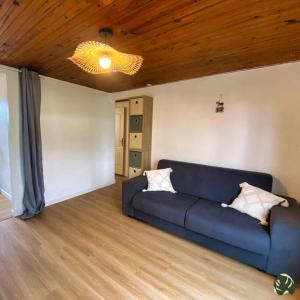 - un canapé bleu dans le salon avec un plafond en bois dans l'établissement La Tit'Kaz Bégonia (Vue montagne), à Saint-Philippe