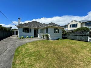a house with a grass yard in front of it at Charming & Modern 4 BR in Lower Hutt