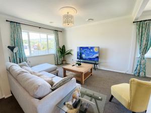 a living room with a couch and a tv at Charming & Modern 4 BR in Lower Hutt