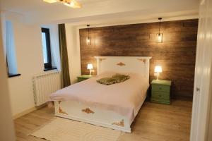 a bedroom with a white bed with a wooden wall at Pensiune Agroturistica Molidu in Almaş