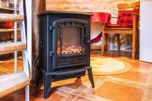 a black stove in a room with a fireplace at Le Pigeonnier - Piscine - Jardin - Calme in Labastide-de-Lévis