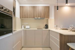 a kitchen with white counters and wooden cabinets at YOUR HOME- Apartment Camp Nou Baj in Hospitalet de Llobregat