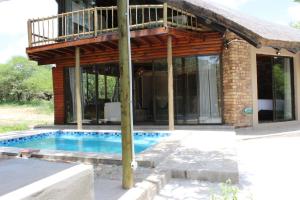ein Haus mit einem Pool und einem Balkon in der Unterkunft Letoane@krugerpark in Marloth Park