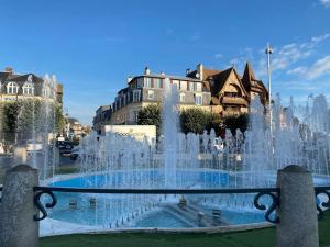 una fuente en una ciudad con edificios en el fondo en Le Duc - Centre ville Parking Deauville, en Deauville