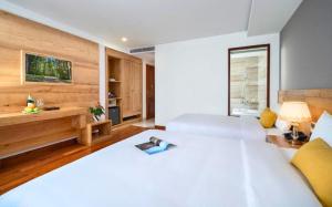 Un dormitorio con una gran cama blanca con un libro encima. en Sunny Ocean Hotel & Spa, en Da Nang 33 fotos más