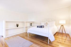um quarto branco com uma cama branca e piso em madeira em Alma Peregrina - Casas de Campo em Junqueira