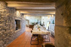 a dining room with a long table in a stone wall at Alma Peregrina - Casas de Campo in Junqueira