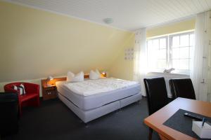 1 dormitorio con cama, escritorio y ventana en Pension Sandra en Neuharlingersiel