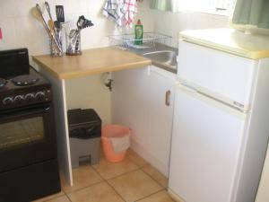 una pequeña cocina con fregadero y nevera blanca en Waterside Living CL07, en Jeffreys Bay 7 fotos más