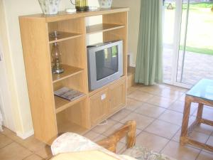 a living room with a tv in a wooden entertainment center at Waterside Living CL07 in Jeffreys Bay