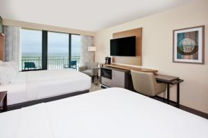 Holiday Inn Va Beach-Oceanside 21st St, an IHG Hotel في فرجينيا بيتش: غرفة فندقية بسريرين وتلفزيون بشاشة مسطحة