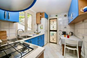 cocina con armarios azules, fregadero y mesa en Rooftop flat in Amalfi, en Amalfi