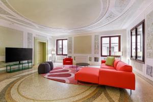 a living room with a red couch and a tv at Palazzo Dei Fiori by Room Mate in Venice