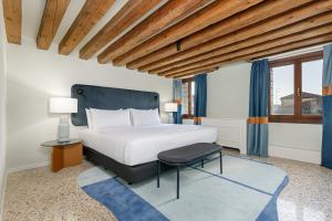 a bedroom with a large bed and a chair at Palazzo Dei Fiori by Room Mate in Venice