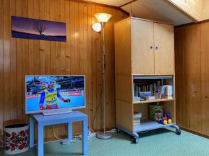 een kamer met een bureau, een televisie en een lamp bij 3-Zi-FeWo Gehrihornblick in Frutigen