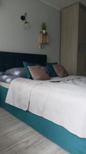 um quarto com uma cama grande com lençóis brancos e almofadas em APARTAMENT USTROŃ 84 em Ustroń
