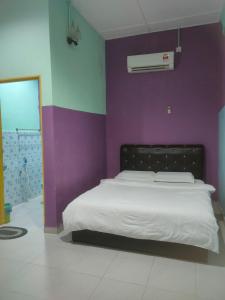 a bedroom with a bed with a purple wall at Taman negara rainbow guest house in Kuala Tahan