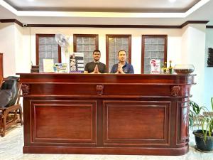 deux hommes se tenant derrière un bar dans une pièce dans l'établissement SISAVANG HOTEL, à Vang Vieng