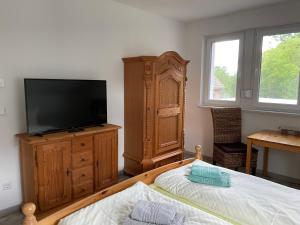 Schlafzimmer mit einem Flachbild-TV und einem Bett in der Unterkunft Urlaub am Plätlinsee - Haus Odin in Wustrow