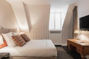 a bedroom with a bed and a desk and a television at De Lindenhoeve Boutique Hotel in Sluis