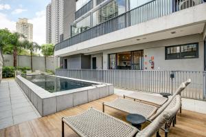 un patio con sillas y una piscina en un edificio en Roomo Brooklyn Studios, en São Paulo