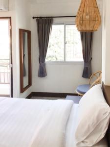 a bedroom with a white bed and a window at บ้านสวนอินทาวน์ Baansuan in Town Hotel in Chiang Mai