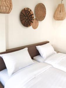 two beds with white pillows and baskets on the wall at บ้านสวนอินทาวน์ Baansuan in Town Hotel in Chiang Mai