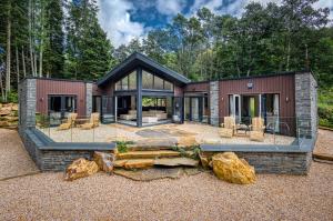 a house in the woods with glass windows and rocks at Heilan Roo in Pitlochry