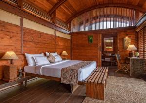 a bedroom with a bed and a bench in a room at Cabo Serai in Canacona