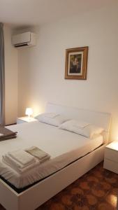 a white bed in a room with a picture on the wall at Casa Stazione Magliana in Rome